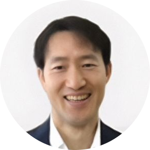短い黒髪の男性が笑顔で写っている、シンプルな背景の丸型プロフィール写真。