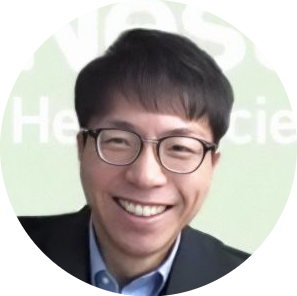 眼鏡をかけた男性が笑顔で写っている、明るい背景の丸型プロフィール写真。